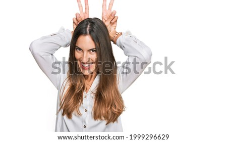 Young beautiful woman wearing casual clothes posing funny and crazy with fingers on head as bunny ears, smiling cheerful 