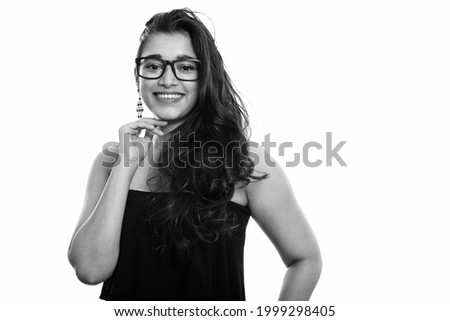 Studio shot of young beautiful Indian woman isolated against white background in black and white