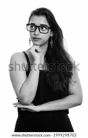Studio shot of young beautiful Indian woman isolated against white background in black and white