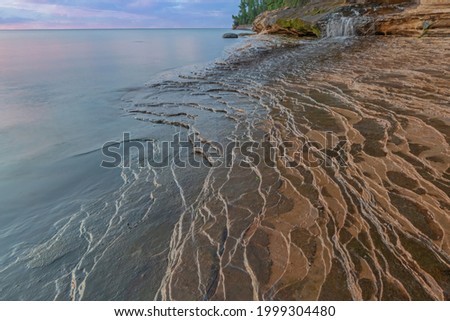 Landscape near sunset of waterfall and the eroded sandstone shoreline at Miner's Beach, Lake Superior, Pictured Rocks National Lakeshore, Michigan's Upper Peninsula, USA