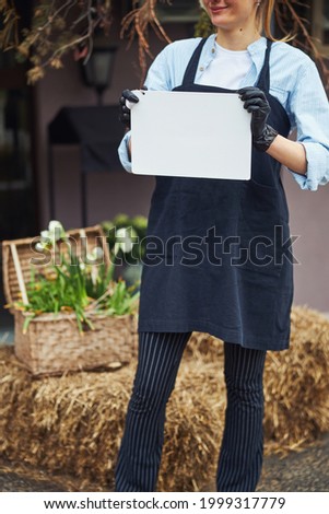 Smiling pleased Caucasian female floriculturist standing outside