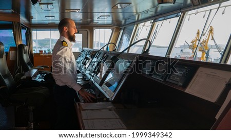 Navigational merchant officer watching keeping navigational watch on the bridge and watching ECDIS and radar Royalty-Free Stock Photo #1999349342