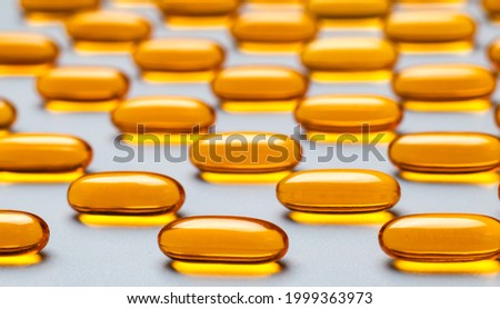 Yellow capsules omega-3 on a gray background. Pattern. Pantone colors of 2021.