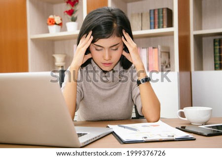 Portrait of tired young Asian business woman while using laptop computer at office desk. Her tired of monotonous work. Lack of motivation concept.