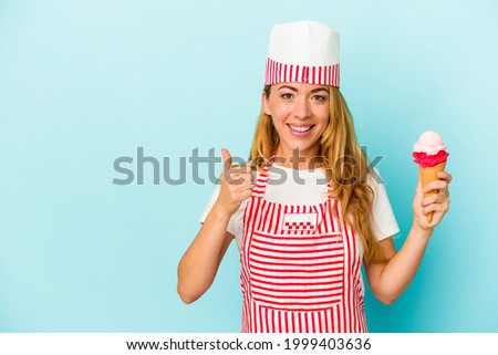 Caucasian ice cream maker woman holding an ice cream isolated on blue background smiling and raising thumb up