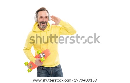 happy mature man skateboarder listen music wearing headphones hold penny skateboard, streetwise.