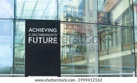 Achieving a decarbonised future  on a city-center sign in front of a modern office building	
 Royalty-Free Stock Photo #1999412162