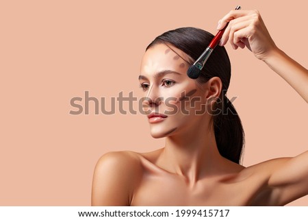 Makeup beauty. Portrait of a beautiful young woman brunette with smooth skin and fresh makeup. Applying  makeup product, contouring and highlighting lines of cheekbones and chin. Makeup angle of youth Royalty-Free Stock Photo #1999415717