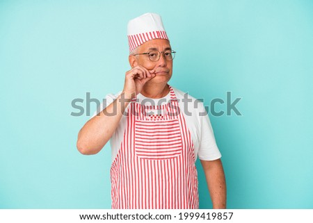 Senior american ice cream man woman holding isolated on blue background with fingers on lips keeping a secret.