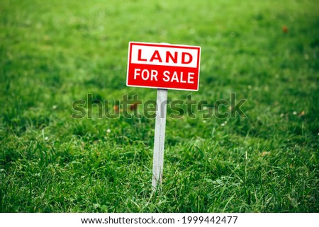 land for sale plate sign, green grass background