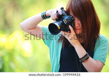 Portrait of beautiful smiling girl,with digital camera in her hands,tone in warm color