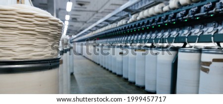 Large round containers with industrial cotton fabric for textile garment production on a machine. Royalty-Free Stock Photo #1999457717