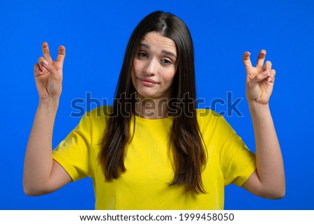 Pretty woman showing with hands and two fingers air quotes gesture, bend fingers isolated over blue background. Not funny, irony and sarcasm concept.