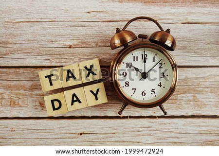 Tax Day Word alphabet letter And Alarm Clock on wooden background