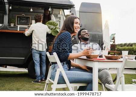 Multiracial people having fun eating at food truck restaurant outdoor - Focus on african man face Royalty-Free Stock Photo #1999478717
