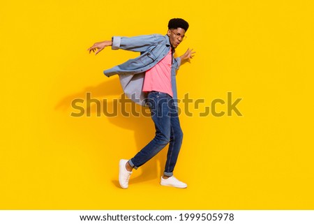 Full body photo of happy cheerful dark skin man fly wind shirt dancer isolated on bright yellow color background Royalty-Free Stock Photo #1999505978