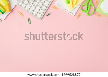 Top view photo of green and yellow stationery organizers pens clips pushpins scissors ruler stickers eraser keyboard and mouse on isolated pastel pink background with copyspace