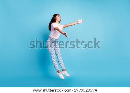 Full size photo of attractive young charming woman open hands empty space jump isolated on blue color background Royalty-Free Stock Photo #1999529594