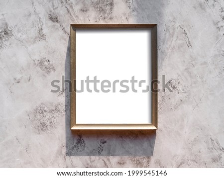Empty gold picture frame hanging on a gray wall. Blank poster mockup for art display in sunlight. Minimalistic interior design. Summer design. Copy space.