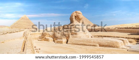 The iconic Sphinx carving adjacent to the Great Pyramids at Giza, Egypt. The great ancient Sphinx on a blue background. side view Royalty-Free Stock Photo #1999545857