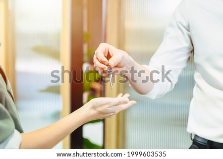 Male hand giving return apartment or home room key to women. couple divorce split home concept.