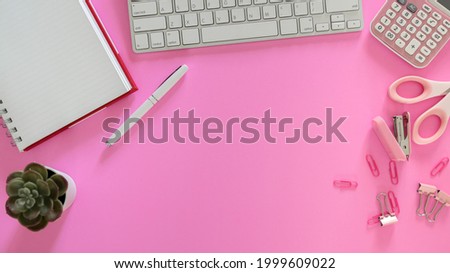 Office supplies placed on a pink background
