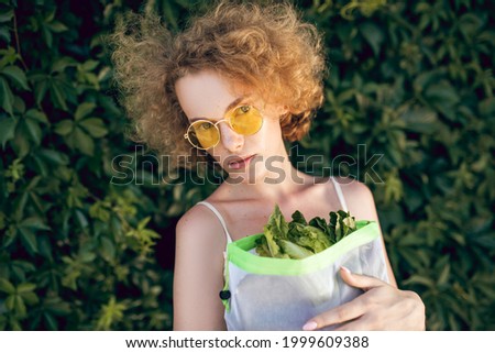 A picture of a young woman with a pack of greens in her hands
