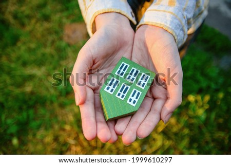 Hands holding green wood house, rental of real estate