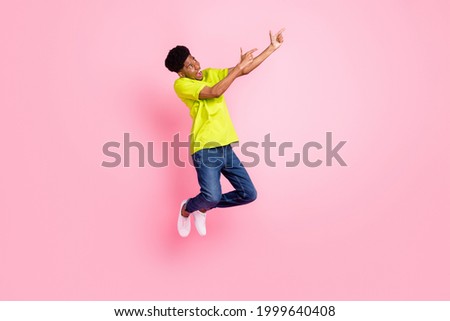 Full size photo of afro american young man point finger empty space jump isolated on pink color background