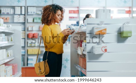 Pharmacy Drugstore: Portrait of a Beautiful Black Young Woman Choosing to Buy Medicine, Drugs, Vitamins. Apothecary Full of Health Care, Pill Bottles, Beauty Cosmetics Products with Modern Design Royalty-Free Stock Photo #1999646243