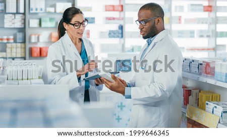 Pharmacy: Black Male and Caucasian Female Pharmacists Use Digital Tablet Computer Talk about Medicine, Drugs, Vitamins, Supplements, Vaccine, Health Care Products. Medical Professionals in Drugstore