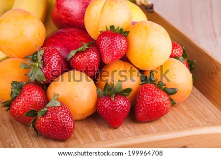 Ripe strawberries and apricot on a wooden background 