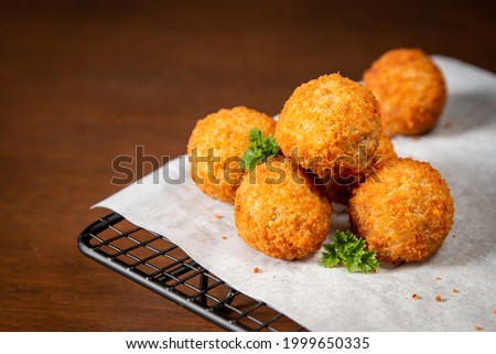 Typical Dutch snacks, bitterballen with baking paper and a oven rack on a wooden surface. Royalty-Free Stock Photo #1999650335