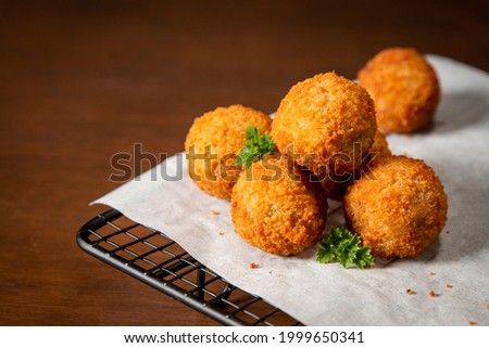 Typical Dutch snacks, bitterballen with baking paper and a oven rack on a wooden surface. Royalty-Free Stock Photo #1999650341
