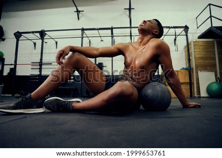 African American male resting on the gym floor after an intense cross training session. Male athlete looking exhausted after the workout. High quality photo