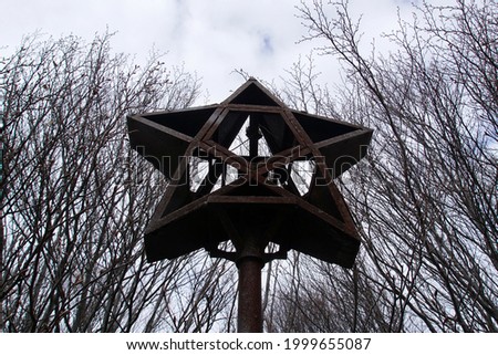 An old metal star on Bratan peak in Sredna Gora, Bulgaria, against the backdrop of tree branches.