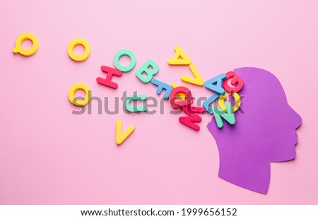 Paper human head with letters on color background. Dyslexia concept Royalty-Free Stock Photo #1999656152
