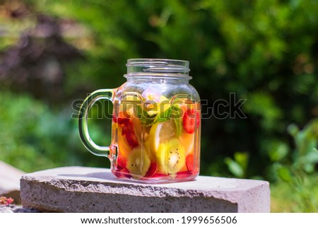 Two Jars of glass, delicious detox drink with red, orange and yellow fruits, standing on the Stone. Selective Focus Glasses.