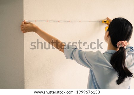 Asian woman measuring the size of the wall
 Royalty-Free Stock Photo #1999676150