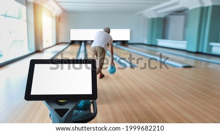 Control panel computer with white blank screen  on bowling sport club with rear view older caucasian man white hair playing bowling in sport club