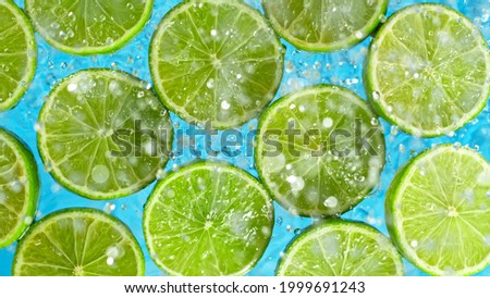 Fresh limes falling into water with splash