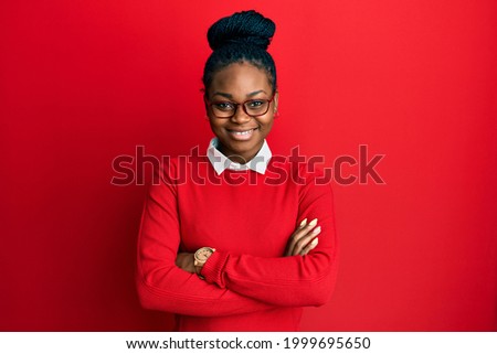 Young african american woman wearing casual clothes and glasses happy face smiling with crossed arms looking at the camera. positive person. 