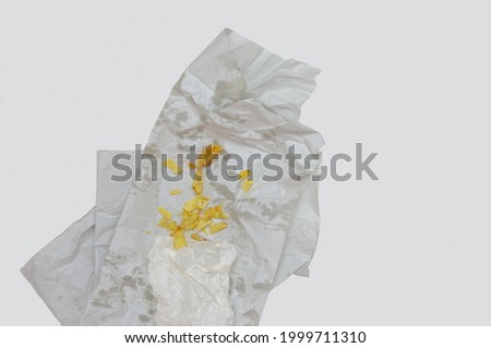 British Chips on Standard Grease Proof Paper, Showing the Common Fried Leftovers on an Oil and Vinegar Stained Takeaway Wrapping.   Royalty-Free Stock Photo #1999711310