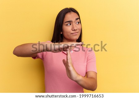 Young mixed race woman isolated on yellow background showing a timeout gesture.