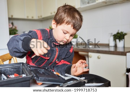 Boy is looking for tools in the toolbox while handyman playing in the kitchen