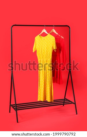 Stylish hanger with female clothes on color background