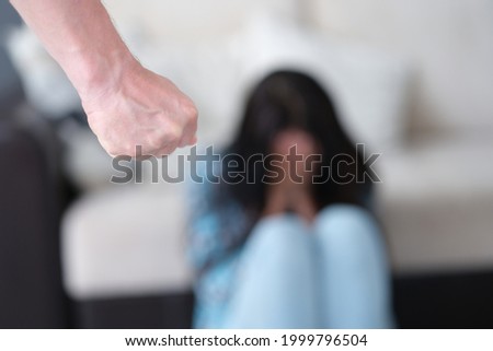 Man stands with fist clenched against background of crying woman Royalty-Free Stock Photo #1999796504