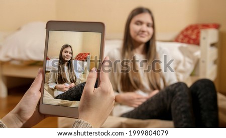 Beautiful teenage girl posing for photographs in social media at home. Modern communication, social media and gadgets.