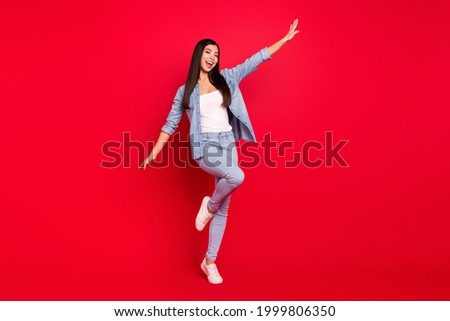 Full length body size view of attractive cheerful girl having fun flying like plane tour isolated over bright red color background