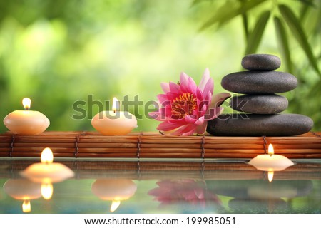 Spa still life with burning candles,zen stone and bamboo mat reflected in a serenity pool Royalty-Free Stock Photo #199985051